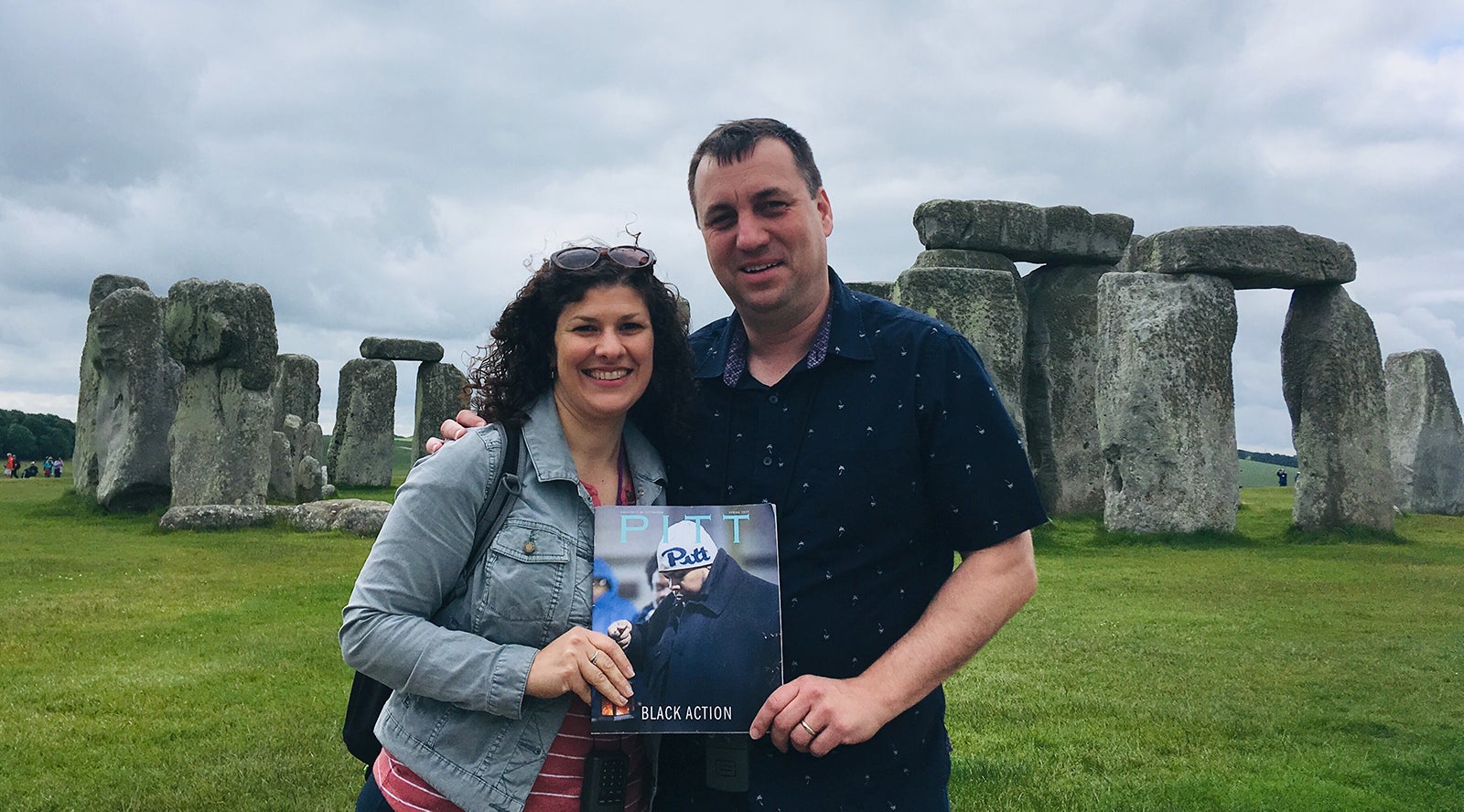 dark-haired main and woman hold Spring 2019 issue of Pitt Magazine in front of Stonehenge