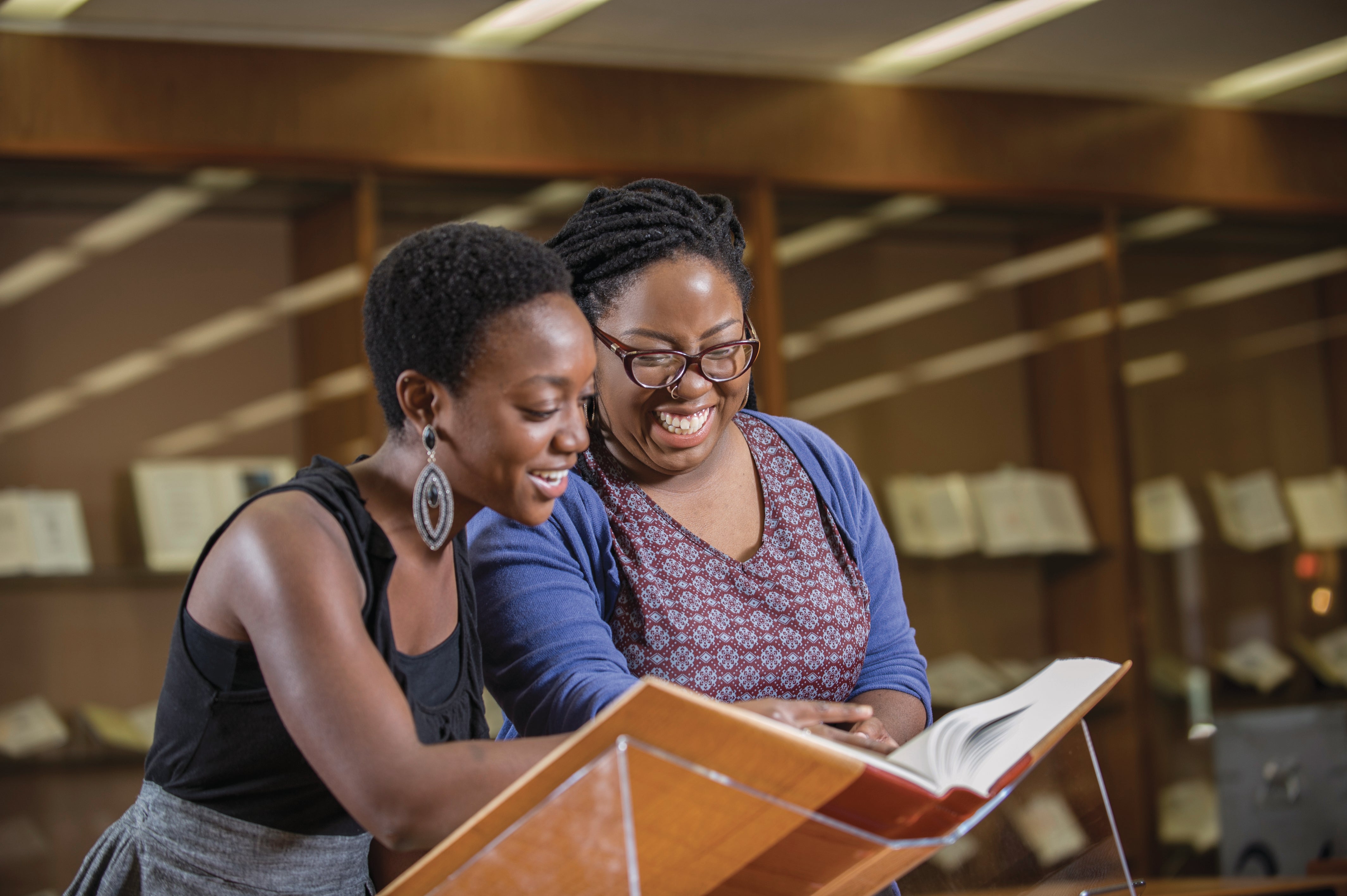 Two Black women look at a book in the library's archives and special collections.