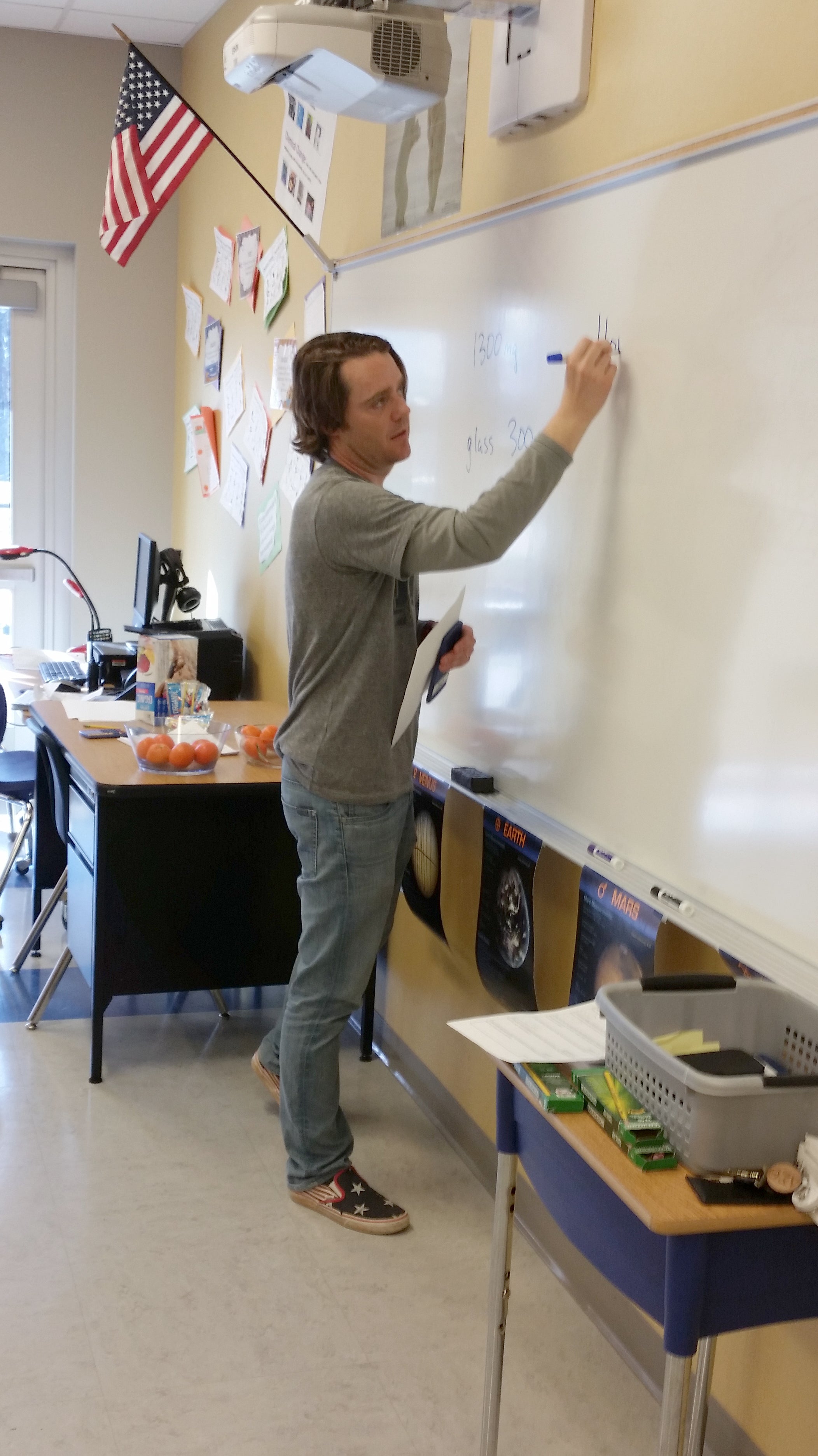 Andrew Van Fossen writes on a whiteboard in a classroom.