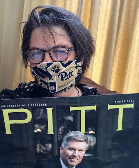 woman wearing Pitt fabric mask reading Winter 2015 issue of Pitt Magazine (picturing Patrick Gallagher)